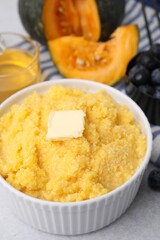 Tasty cornmeal with butter in bowl on table, closeup