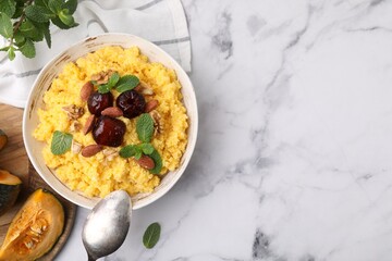 Tasty cornmeal with dates, nuts and mint in bowl served on white marble table, top view. Space for text