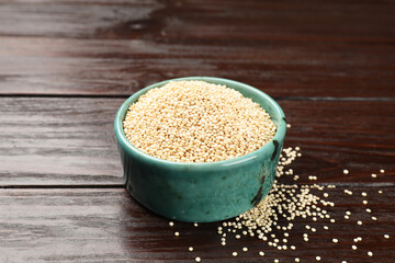 Dry quinoa seeds in bowl on wooden table