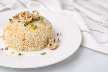 Delicious bulgur with vegetables, mushrooms and microgreens on table, closeup