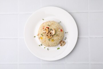 Delicious bulgur with vegetables, mushrooms and microgreens on white tiled table, top view