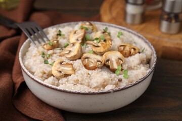 Delicious barley porridge with mushrooms and microgreens in bowl on table, closeup