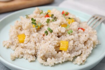 Delicious barley porridge with vegetables and microgreens on table, closeup