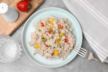 Delicious barley porridge with vegetables and microgreens on gray table, flat lay