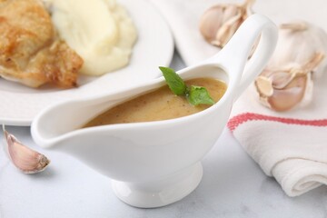 Delicious turkey gravy and garlic on white table, closeup
