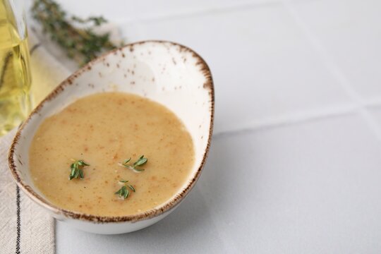 Delicious turkey gravy and thyme on white tiled table, closeup. Space for text