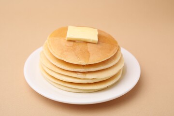 Delicious pancakes with butter and honey on beige background, closeup