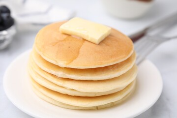 Delicious pancakes with butter and honey on white table, closeup