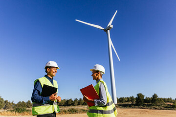 Renewable energy engineers on a field with wind turbines.