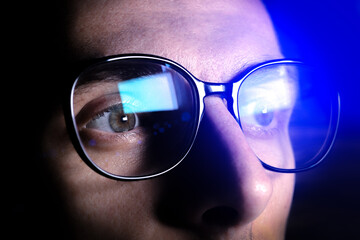 Man works on internet. Reflection at the glasses from laptop..Close up of man's eyes with black female glasses for working at a computer. Eye protection from blue light and rays.