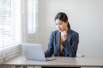 Asian Business woman work on laptop for doing math finance on an office desk, tax, report, accounting, statistics, and analytical research concept
