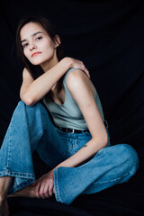 Naklejka premium Beautiful young slender woman in jeans sitting
