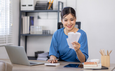 asian woman using calculator and calculate bills in home office. tax form us business income office...