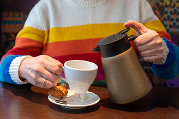 Pouring green tea from a teapot into a white cup