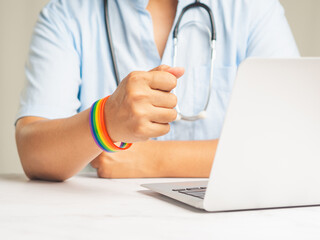 Doctor with a rainbow wristband in a hand while sitting at the table in the hospital