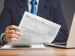 Businessman holding a form 1040. U.S. individual income tax return while sitting at the table