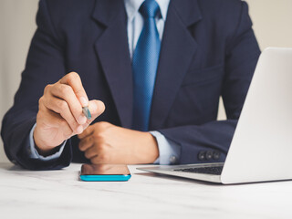 Businessman holding a pen and writing in the air while sitting at the desk