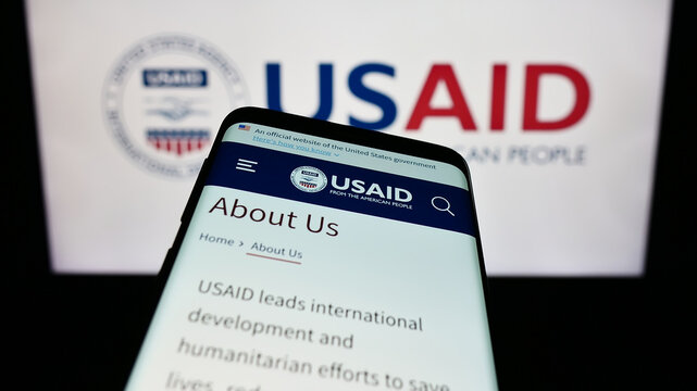 Stuttgart, Germany - 11-27-2023: Smartphone with website of United States Agency for International Development (USAID) in front of logo. Focus on top-left of phone display.