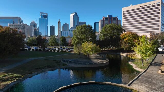Urban park with fountain in downtown Charlotte, North Carolina. Aerial rising shot revealing skyline on bright day.