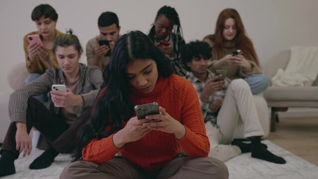 Multiracial group of friends using phone together. People addicted to technology and social media. Multiethnic addicted students ignoring each other. Problem of communication. Phubbing smartphones