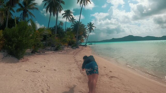 A young man doing a backflip in the sand on the beaches of bora bora island, paradise 