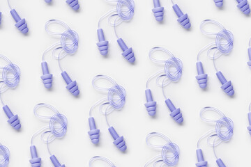 Reusable silicone violet color earplugs, for swim, sleep, rest as minimal trend pattern on white background. Soft, flexible ear plug on cord against noise, protect hear, top view, flat lay