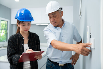 Senior home inspector checking the electrical switch and check defects, before finish handing it over to client. Young engineers learn home inspection with Senior, Real estate and renovation concept.