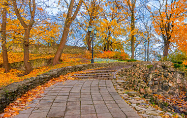 Golden autumn in old city park and staircases leading to the top of artificial hill