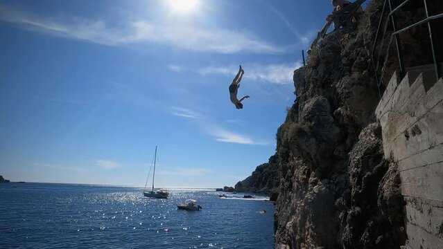  Adventurous young man jumping off a cliff does a backflip in Greece 