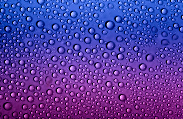Water drops on glass as a background. Condensation on a cold drink. Multicolored background with drops texture.