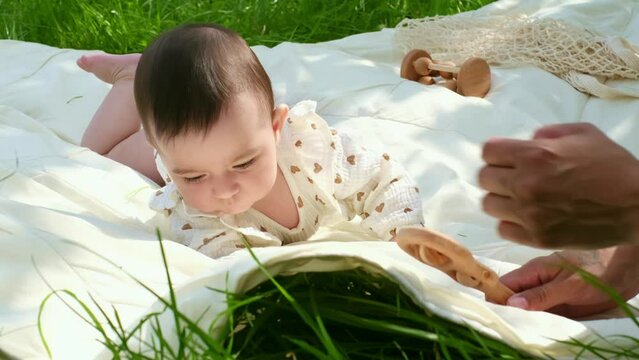 An infant reaches for a wooden rattle, a milestone moment of motor skills development. A scene that resonates with every parent's experience.