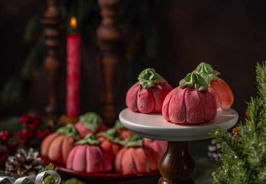 Homemade pink marshmallows in the shape of pumpkins surrounded by Christmas decorations.