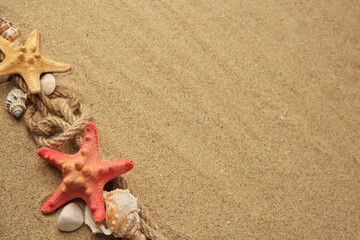 Fototapeta na wymiar Beautiful sea stars, shells and ropes on sand, flat lay. Space for text
