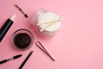 Flat lay composition with eyebrow henna and tools on pink background. Space for text