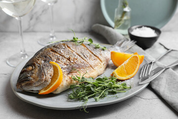 Seafood. Delicious baked fish served with orange and microgreens on light textured table, closeup