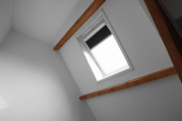 Roof window on slanted ceiling indoors, low angle view