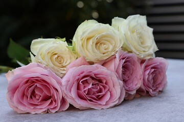 Beautiful bouquet of roses on light grey table outdoors, closeup