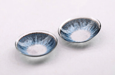 Two blue contact lenses on white background