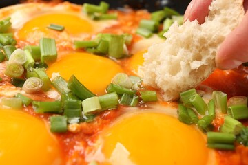 Woman eating delicious Shakshuka with bread, closeup