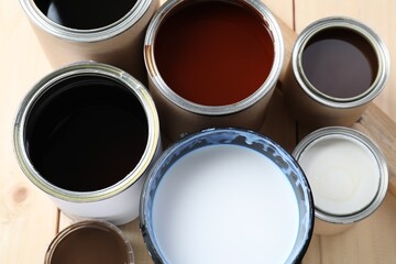 Cans with different wood stains and varnish on wooden surface, flat lay