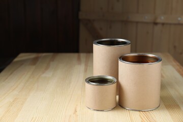 Cans with different wood stains on wooden surface, space for text