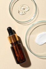 Bottle of cosmetic serum and petri dishes with samples on beige background, flat lay