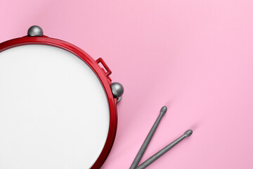 Children's drum with drumsticks on pink background, top view. Space for text