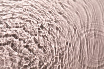 Rippled surface of clear water on beige background, top view