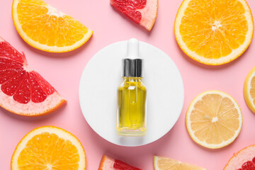 Bottle of cosmetic serum and citrus fruit slices on pink background, flat lay