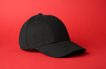 Stylish black baseball cap on red background