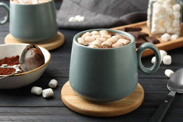 Cup of aromatic hot chocolate with marshmallows served on dark gray wooden table, closeup