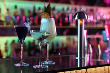 Different fresh alcoholic cocktails on counter in bar. Space for text