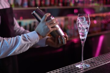 Bartender making fresh alcoholic cocktail at counter in bar, selective focus