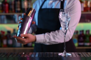 Bartender making fresh alcoholic cocktail at counter in bar, selective focus